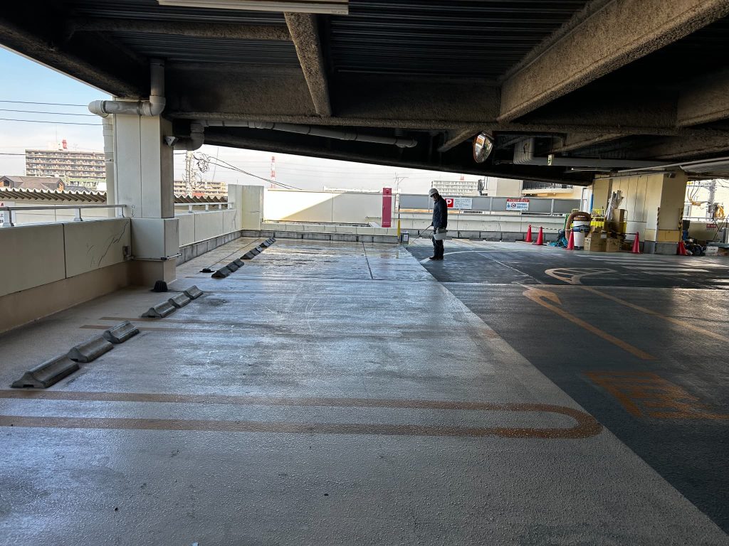 自走式駐車場の床面にシリカテックを施工中。コンクリート内部に浸透し、ひび割れや漏水を防止する防水処理作業
