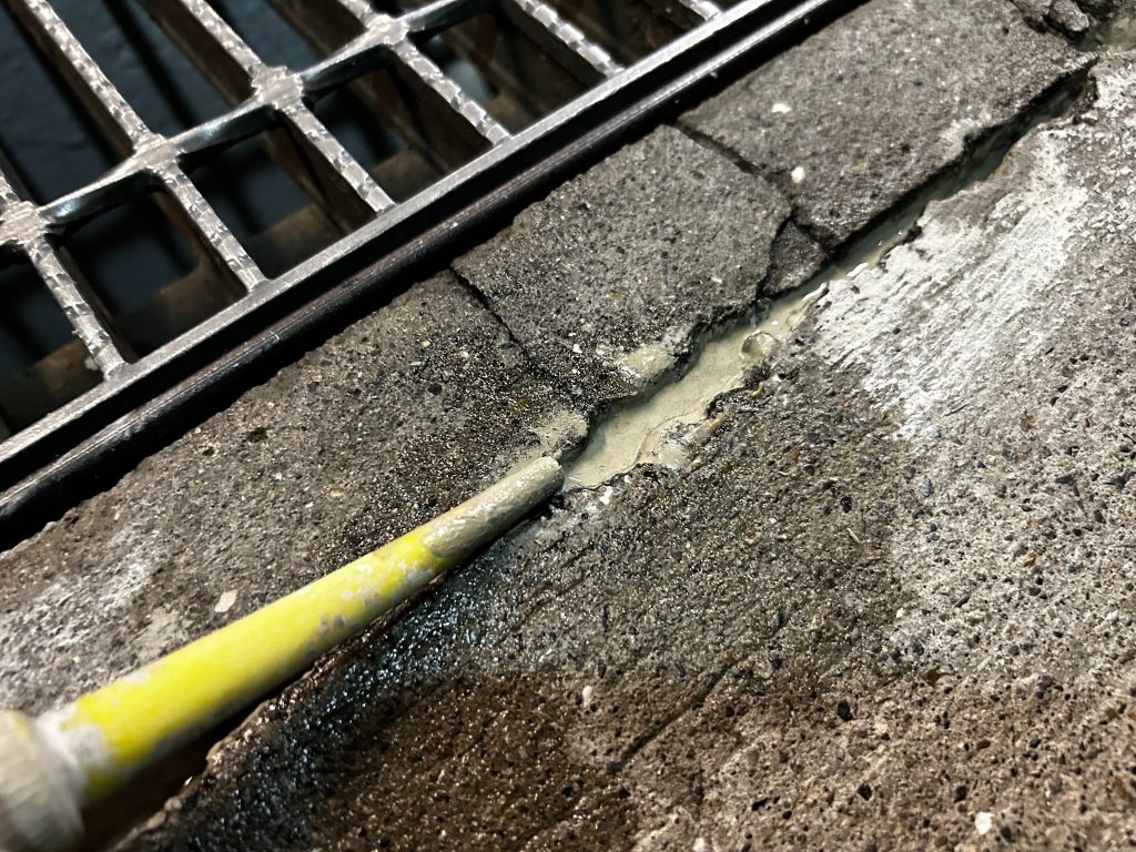 コンクリートのひび割れに補修材を注入して行う止水・防水処理を行う工程