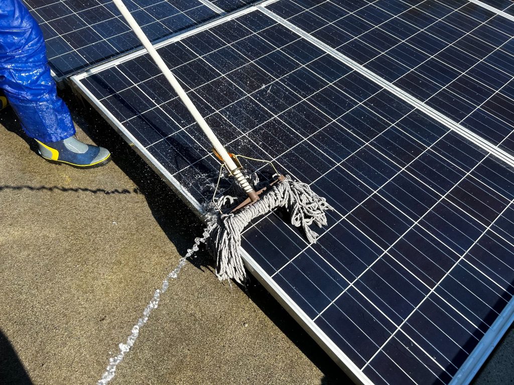 太陽光パネルの表面に付着した汚れやホコリを除去している清掃作業の様子
