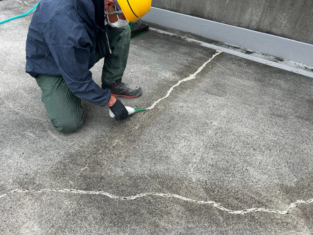 東京都府中市のショッピングモールの立体駐車場。屋上のひび割れ部分にセメント系グラウト材を注入している様子。