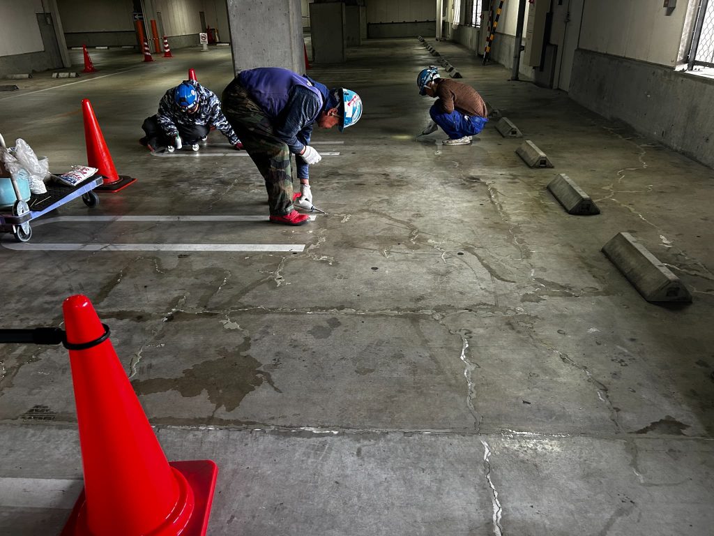 京都府京都市の商業施設駐車場。劣化したコンクリート床のひび割れ部分にセメント系グラウト材を注入して補修している様子。