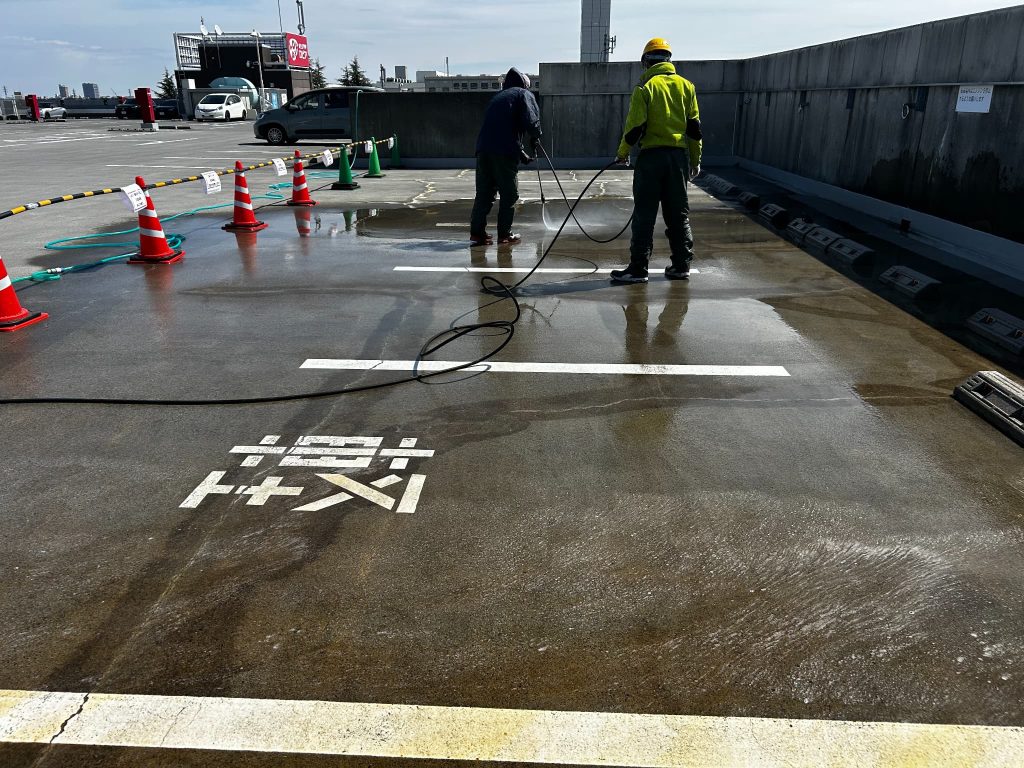 東京都府中市のショッピングモールの立体駐車場。シリカテックの残材を高圧洗浄機で洗浄している様子。