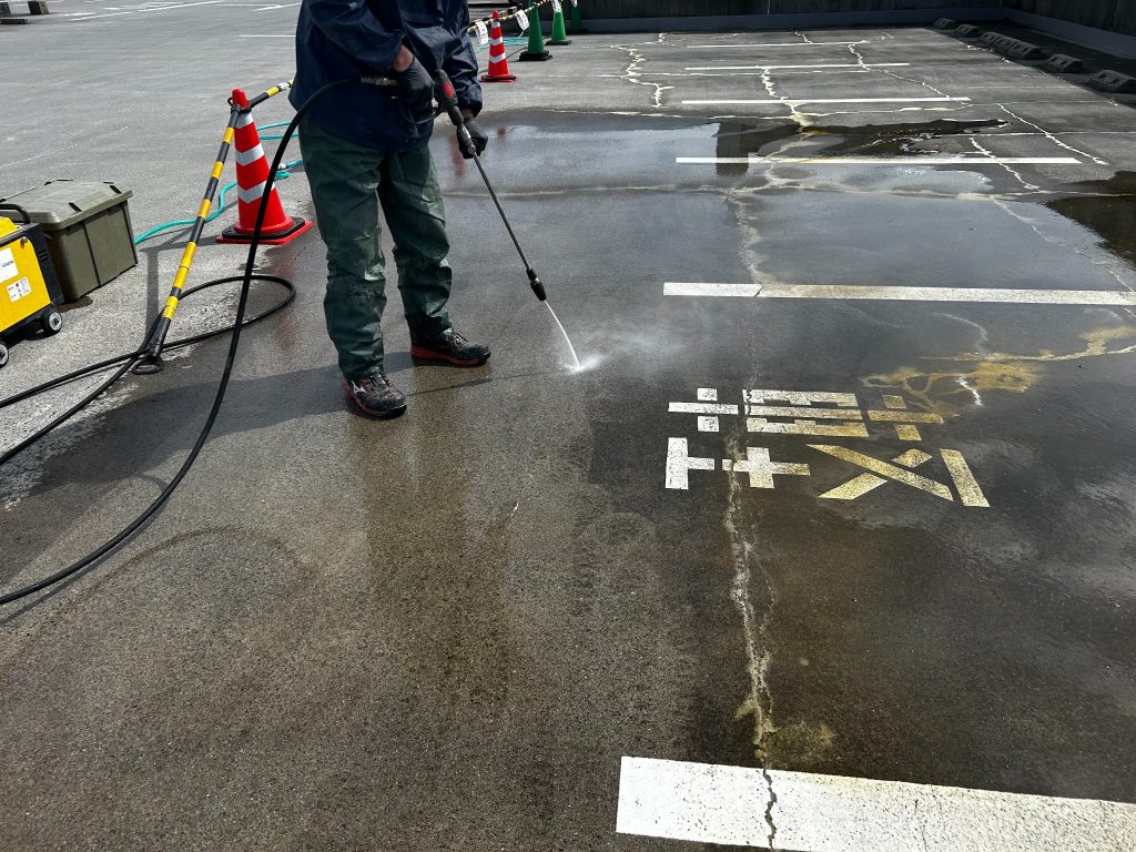 東京都府中市のショッピングモールの立体駐車場。シリカテックの残材を高圧洗浄機で洗浄している様子。