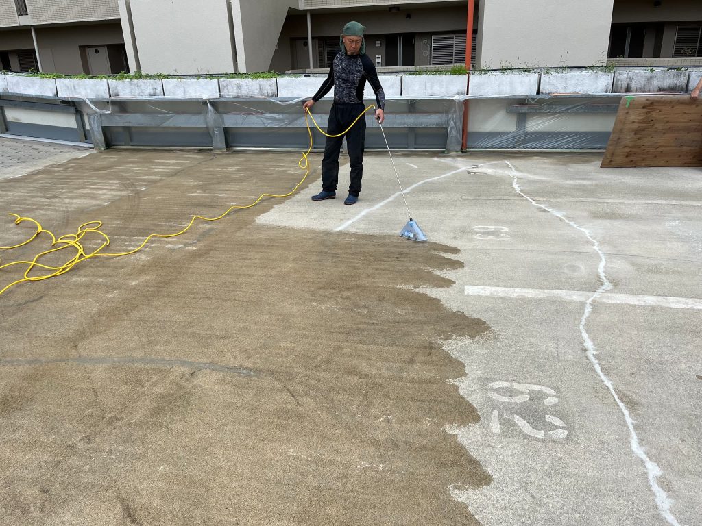 兵庫県神戸市のマンション自走式立体駐車場での雨漏り対策施工。コンクリート部分にシリカテックを散布している様子。