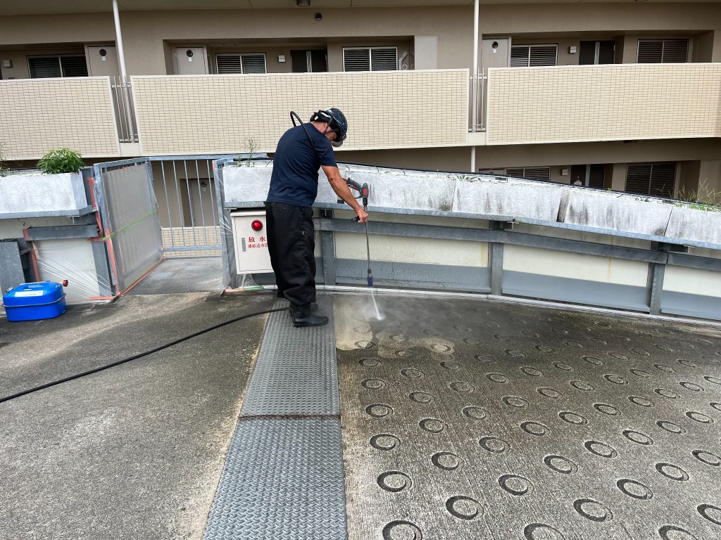 兵庫県神戸市のマンション自走式立体駐車場での雨漏り対策施工。スロープ部分のコンクリート表面の汚れを除去するために高圧洗浄機で掃除している様子。