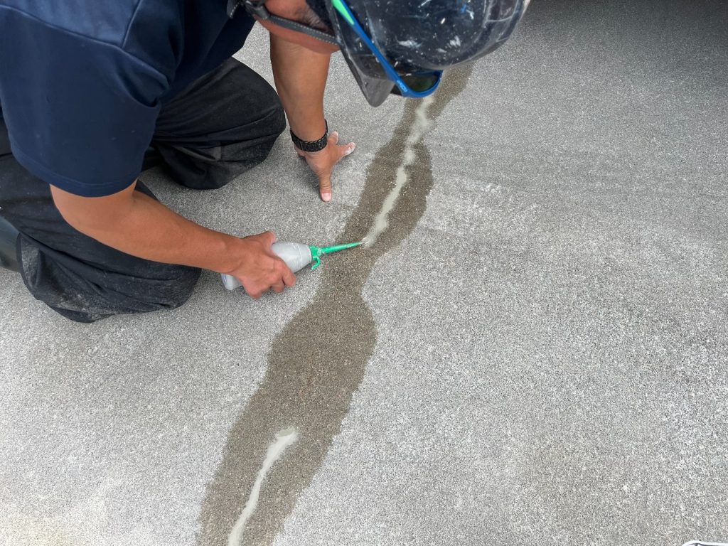 兵庫県神戸市のマンション自走式立体駐車場での雨漏り対策施工。ひび割れ部分にセメント系グラウト材を注入している様子。